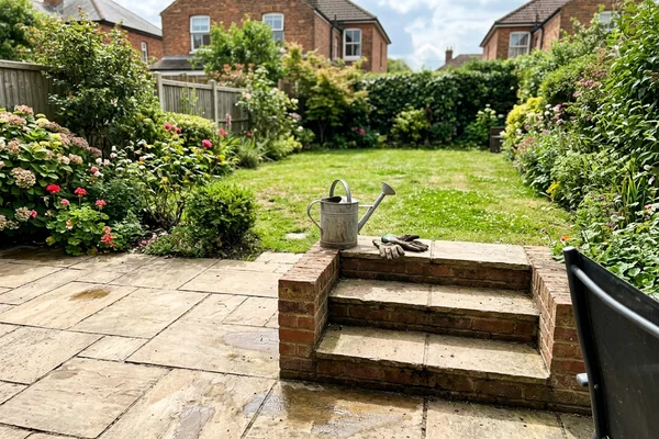 Indian sandstone patio with brick built steps leading down to a lawn