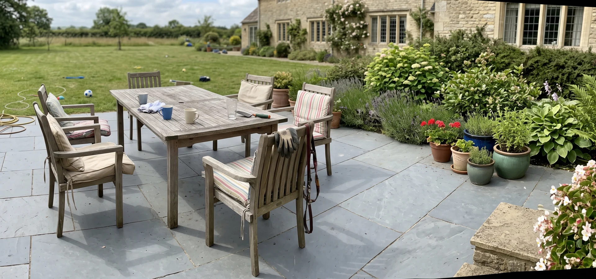 Large porcelain patio with garden furniture behind a Gloucestershire house